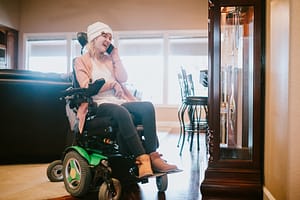 Cheerful Woman In Wheelchair on Smartphone At Home